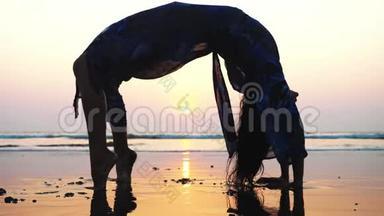 年轻女子在海滩上做体操<strong>桥</strong>的<strong>剪影</strong>